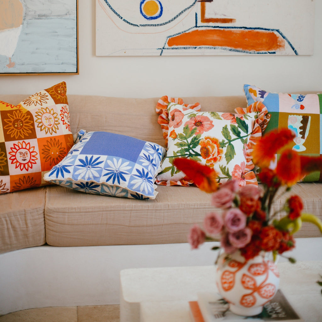 jumbled x bonnie and neil linen cushion. Hand painted blue and white flowers in a border around the cushion. Finished with a scallop trim.